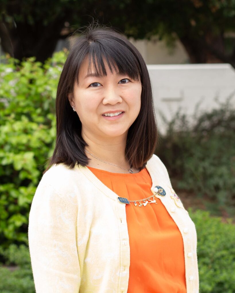 A person with long black hair wearing an orange shirt.